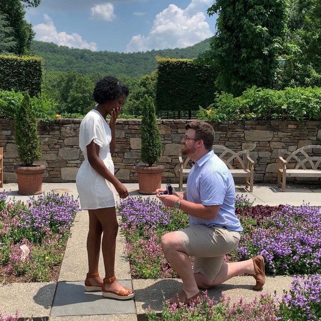 man proposing to woman on one knee. women is surprise and has hand over mouth